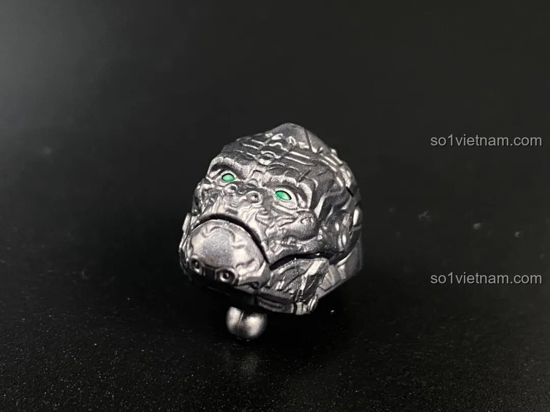 Phần đầu của mô hình Optimus Primal dạng thú với miệng ngậm, thể hiện vẻ mặt trầm tư và quyền lực.