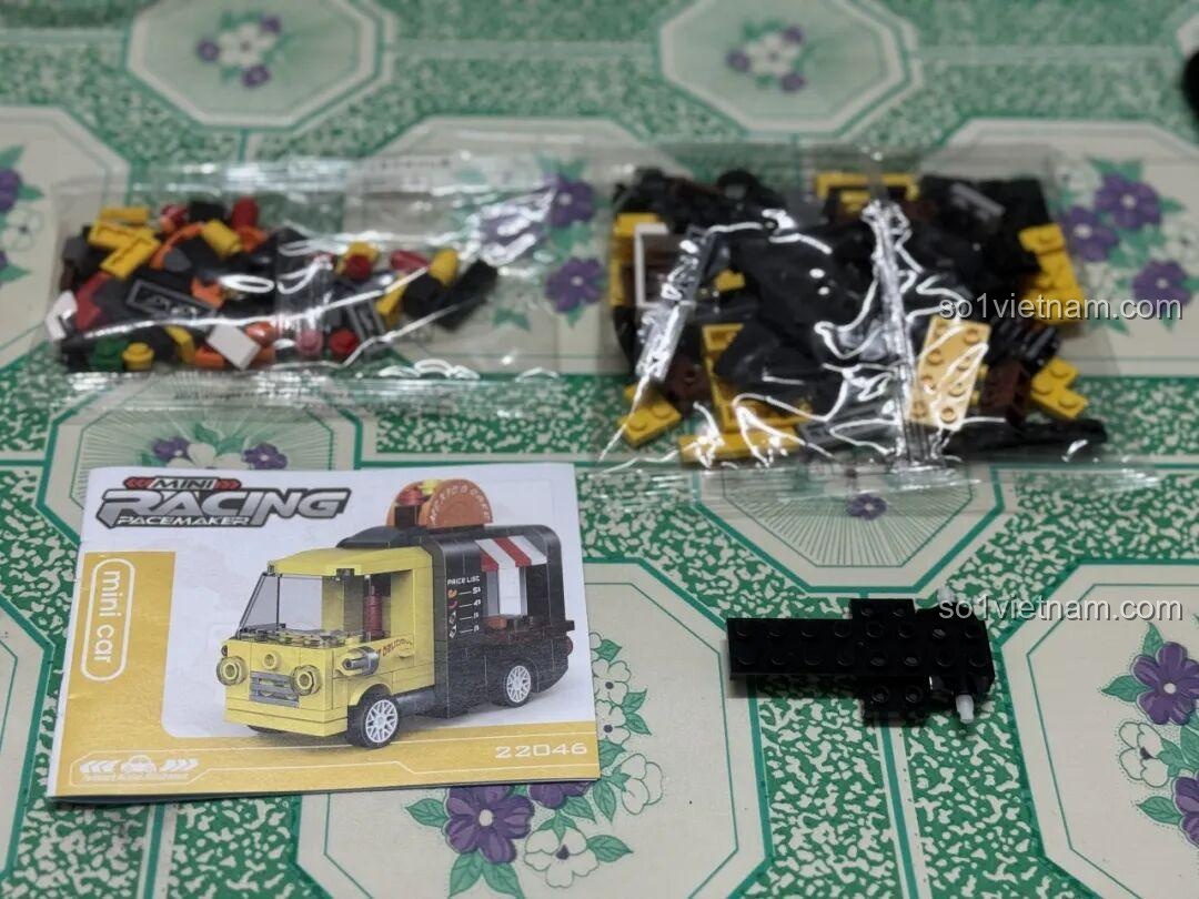 Bên trong hộp Xe Bán Đồ Ăn Kéo Lùi 22046, bao gồm các túi mảnh ghép, sách hướng dẫn và khung động cơ kéo lùi, giá tiết kiệm.