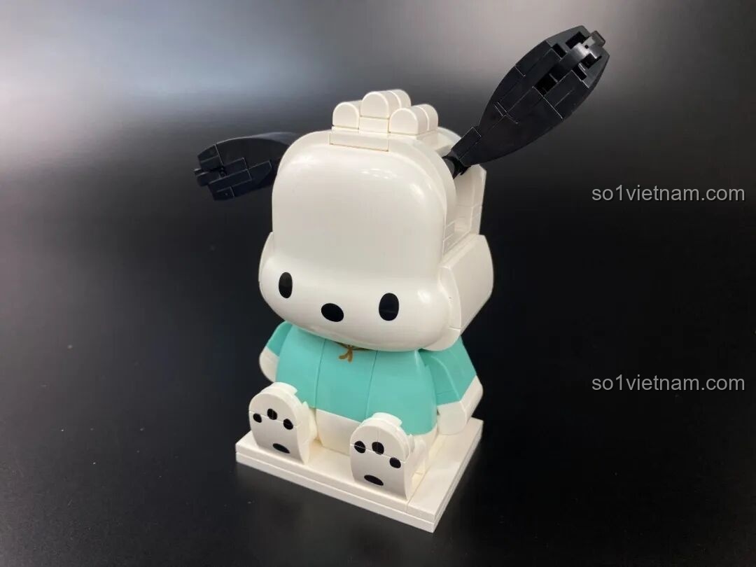 Gắn mảnh ghép mặt in sẵn vào phần đầu của mô hình Pochacco, một bước quan trọng để tạo linh hồn cho nhân vật.