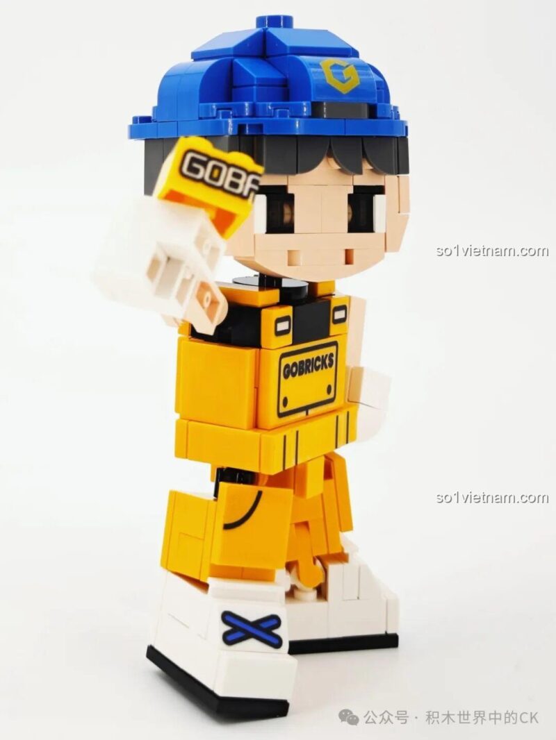 Gobricks G2411 Nhân vật lắp ghép màu vàng, đội mũ xanh, cầm viên gạch Gobricks, nhìn nghiêng