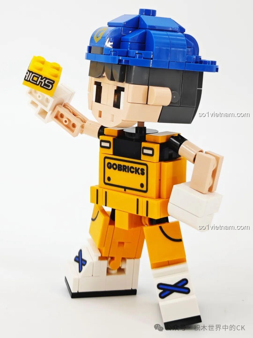 Gobricks G2411 Nhân vật lắp ghép màu vàng, đội mũ xanh, cầm viên gạch Gobricks