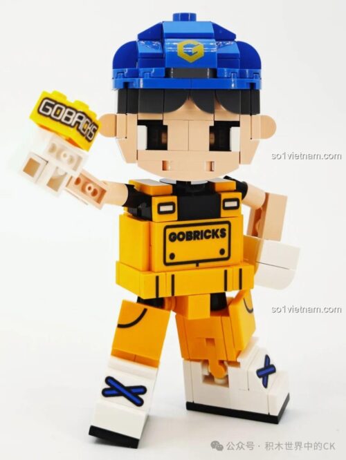 Gobricks G2411 Nhân vật lắp ghép màu vàng, đội mũ xanh, cầm viên gạch Gobricks, tư thế năng động