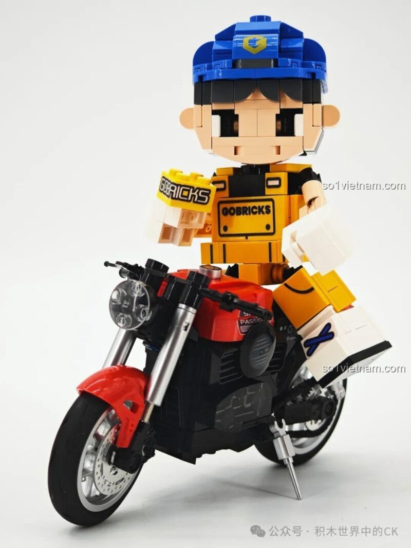 Gobricks G2411 Nhân vật lắp ghép màu vàng, đội mũ xanh, đứng cạnh nhân vật Woody