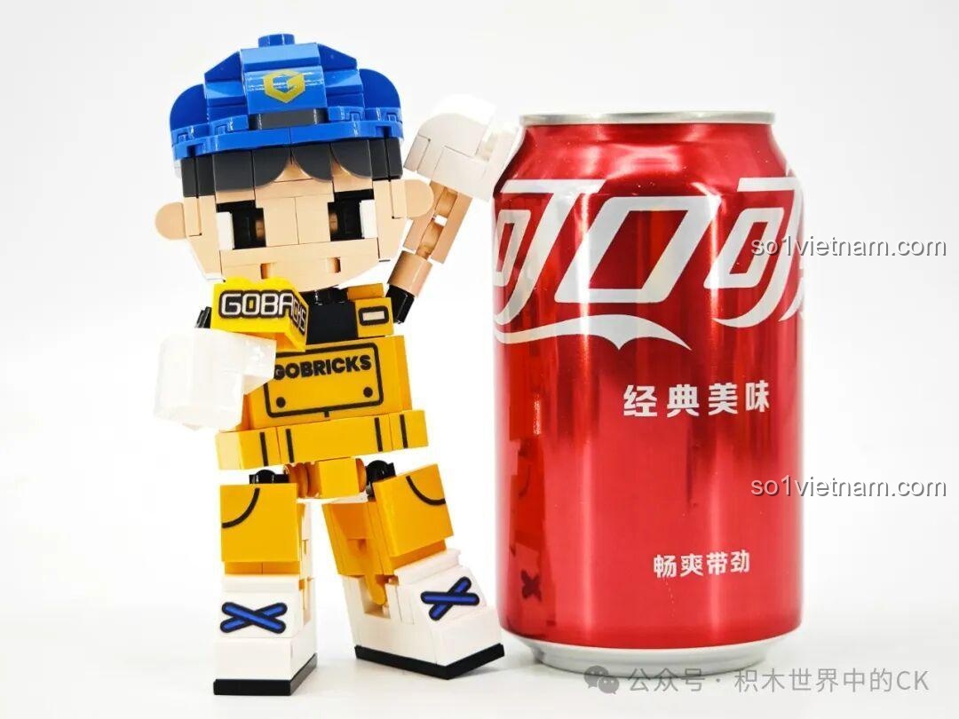 Nhân vật lắp ráp Gobricks G2411 đứng cạnh lon nước ngọt lớn