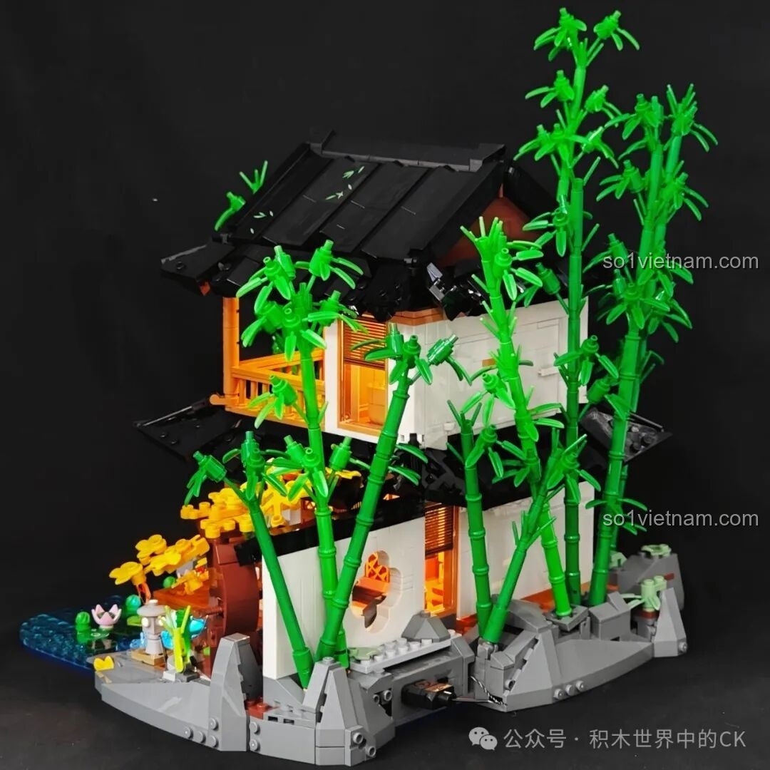 Một góc nhìn khác của mô hình Nhà Trọ Rừng Trúc L9075 khi lên đèn, làm nổi bật hồ nước và cây hoa vàng.