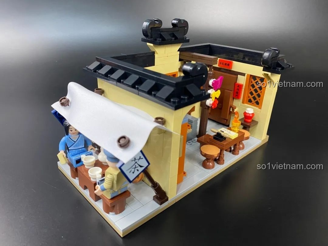 Góc nhìn cận cảnh quán trà nhỏ với các nhân vật đang ngồi thưởng trà.