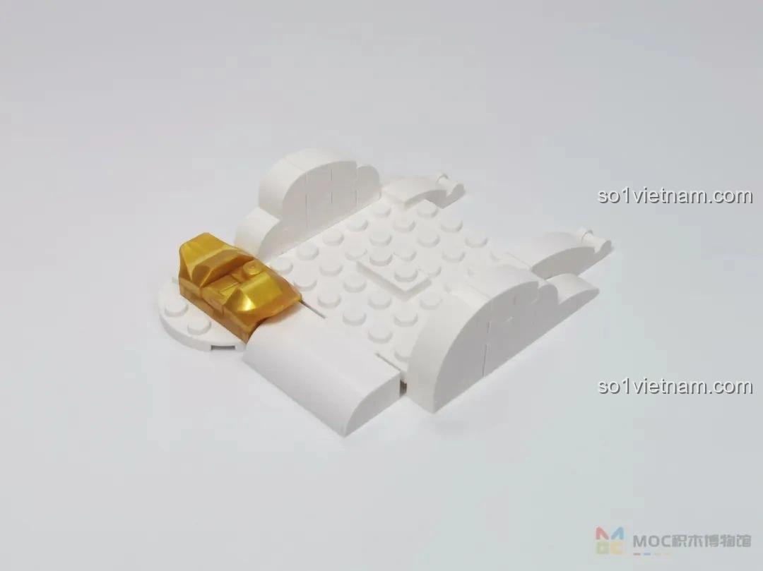 Phần đế của mô hình JAKI JK20236 Kỳ Lân Chiêu Tài đang được lắp ráp, với các mảnh ghép màu trắng và vàng đồng.