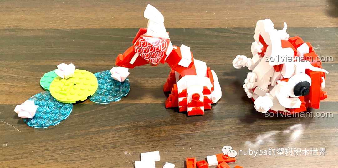 Các bộ phận riêng lẻ của mô hình JAKI Lucky Koi gồm đầu, thân, đuôi và đế, chuẩn bị cho bước lắp ráp cuối cùng.