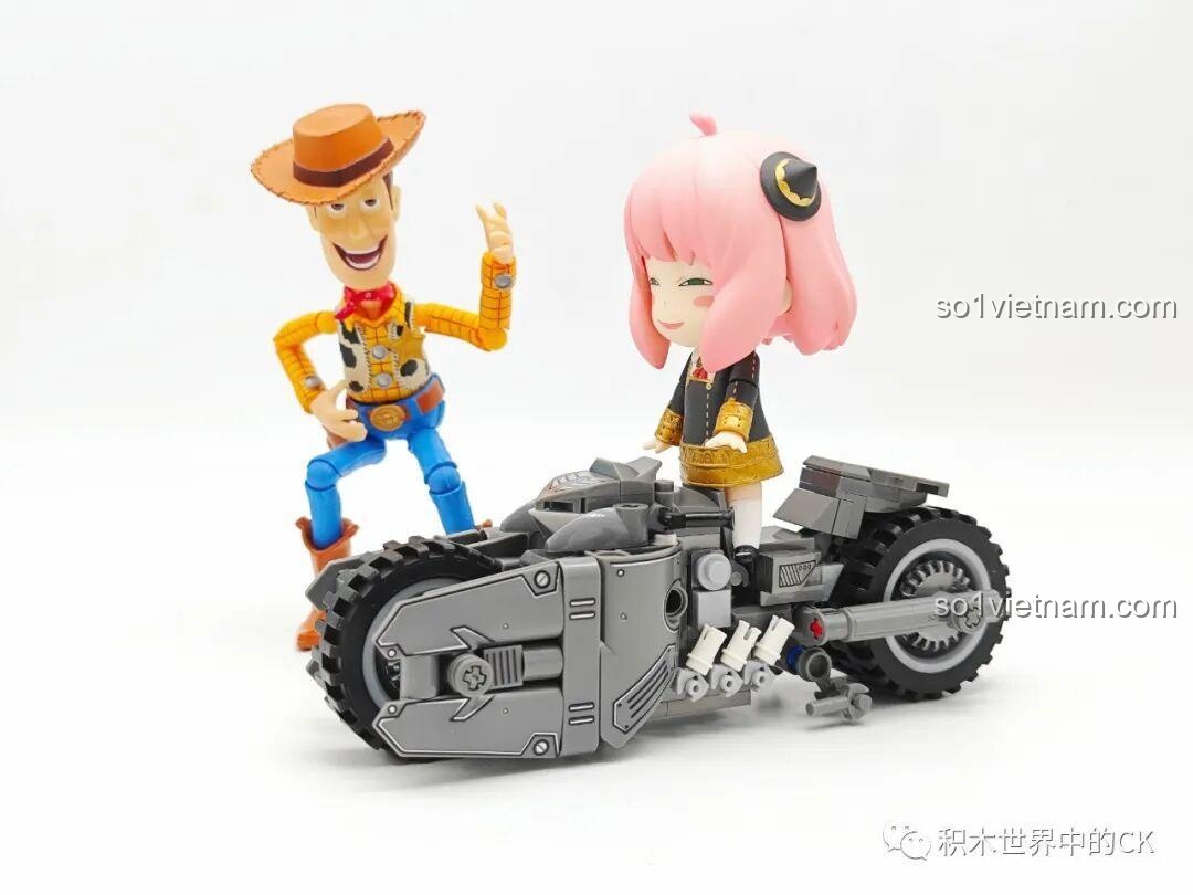 Nhân vật Anya Forger đứng cạnh mô hình JIESTAR 58051 Batcycle, cho thấy kích thước phù hợp để chơi cùng các nhân vật nhỏ.