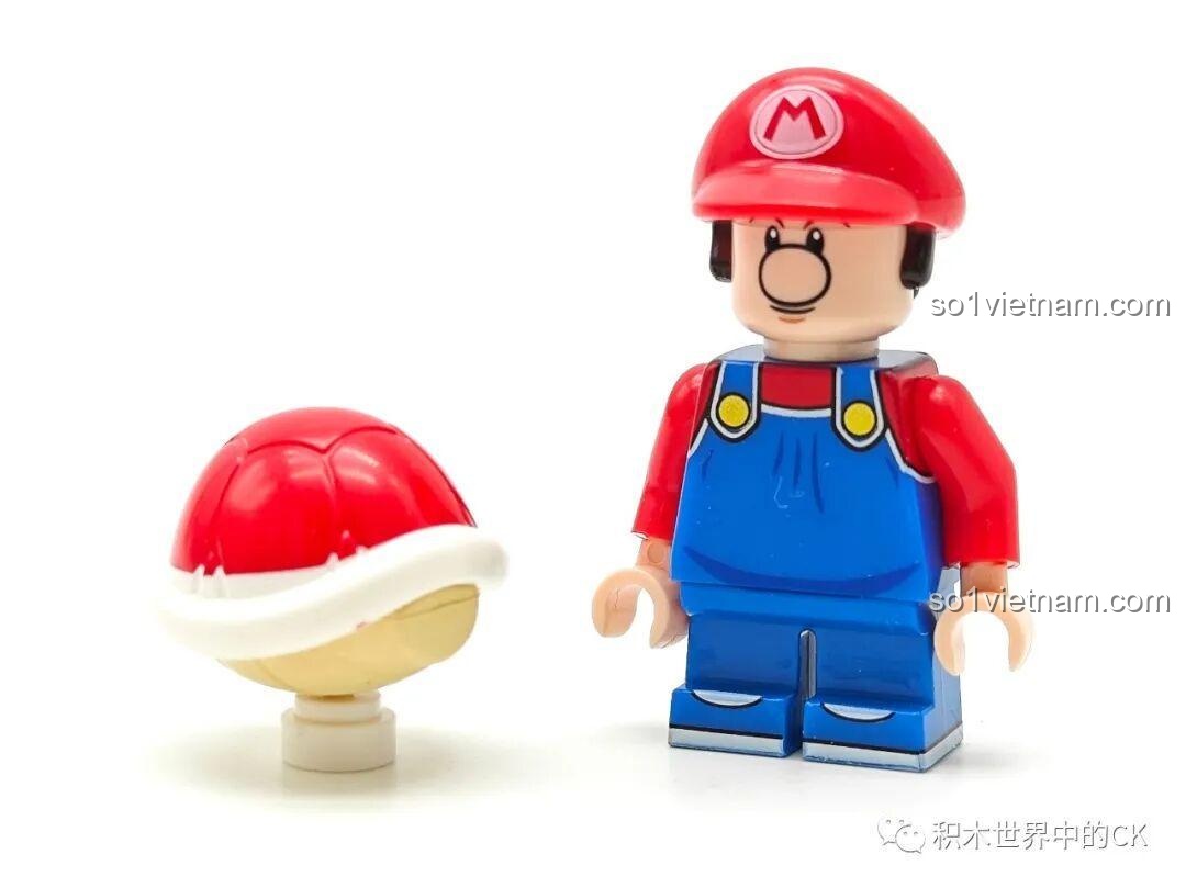 Minifigure Baby Mario (K2119) từ bộ đồ chơi Mario và bạn bè 815 siêu tiết kiệm, đứng cạnh Red Koopa Shell, nhìn từ phía trước.