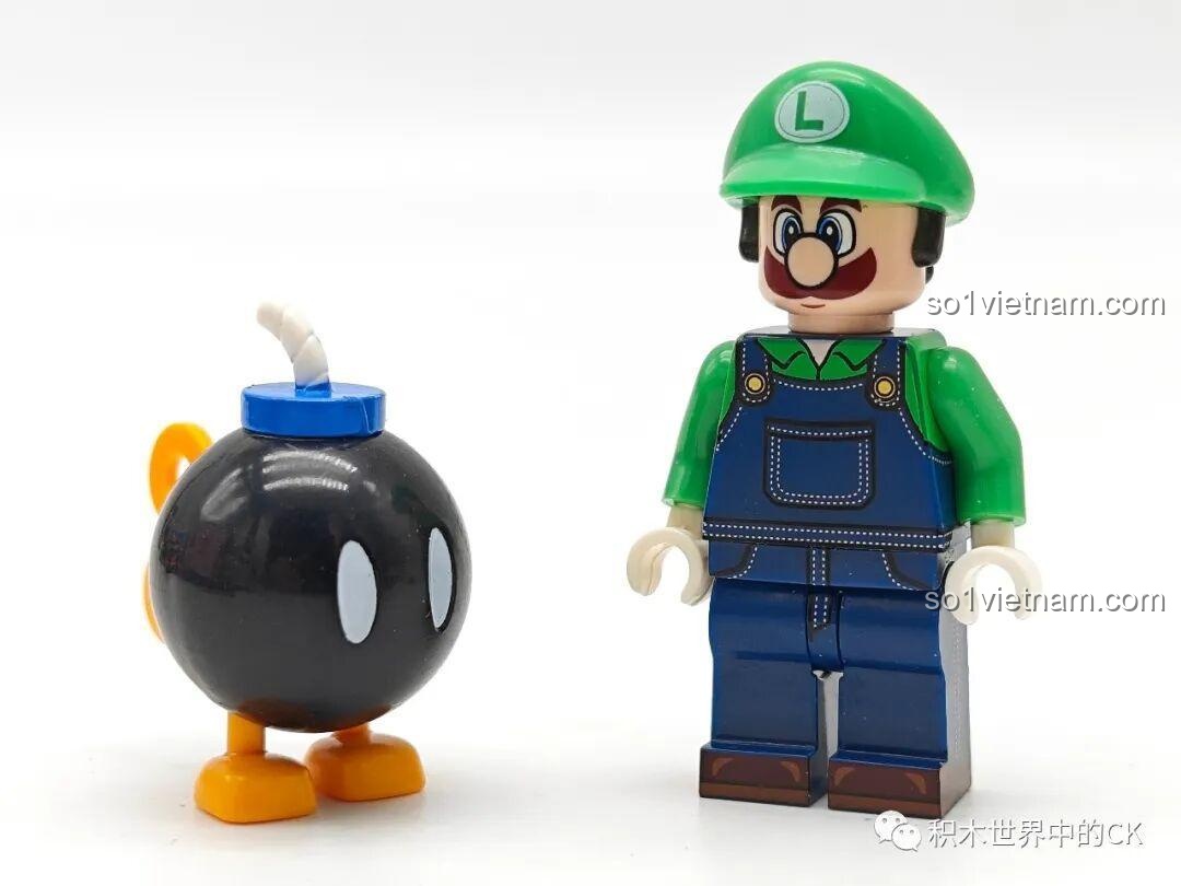 Minifigure Luigi (K2118) từ bộ đồ chơi Luigi KDL tiết kiệm, đứng cạnh Bob-omb đen tròn, nhìn từ phía trước.