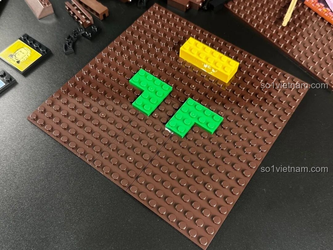 Quá trình lắp ráp phần đế của bộ Pantasy Gramophone 85009, với các mảnh ghép màu nâu và xanh lá cây, bắt đầu hình thành mô hình máy hát đĩa.