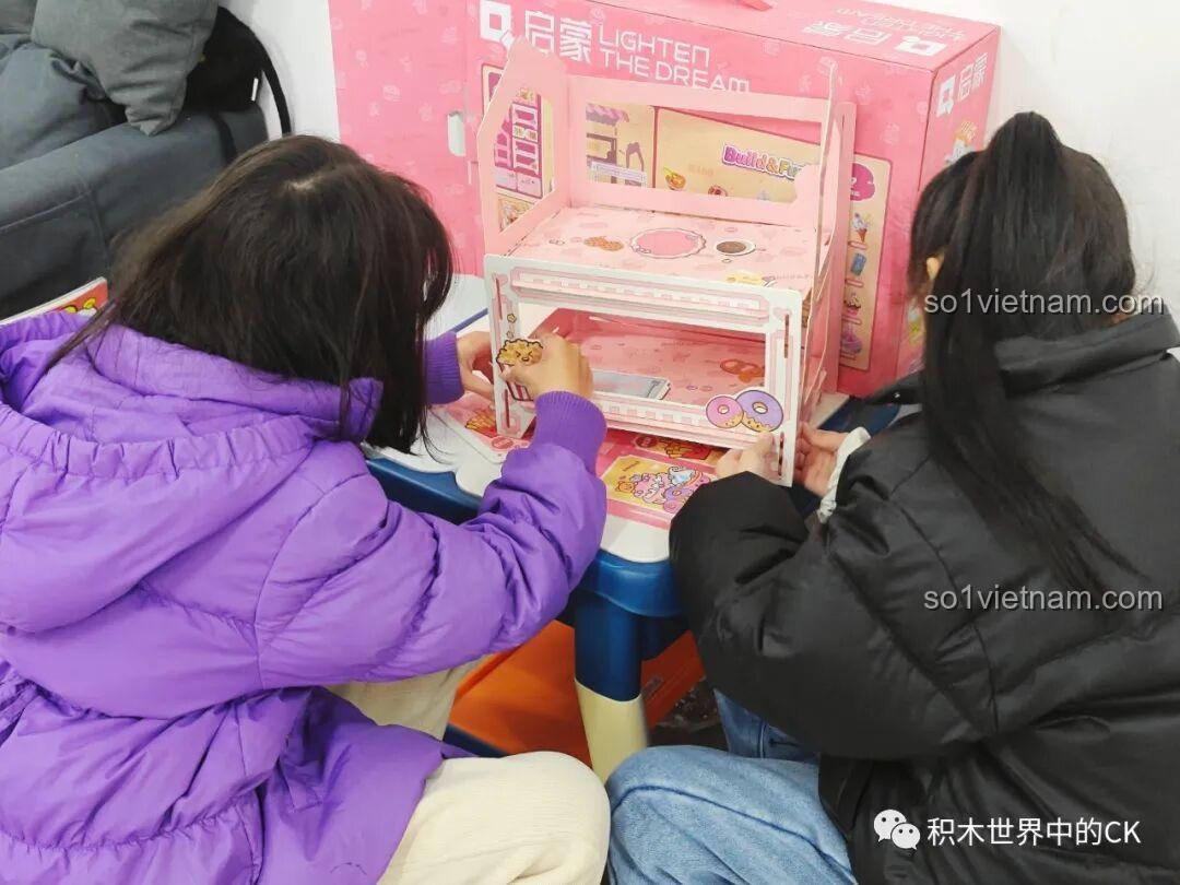 Các bé gái đang trang trí cho chiếc kệ trưng bày của bộ QMAN 35018 bằng các sticker đi kèm.