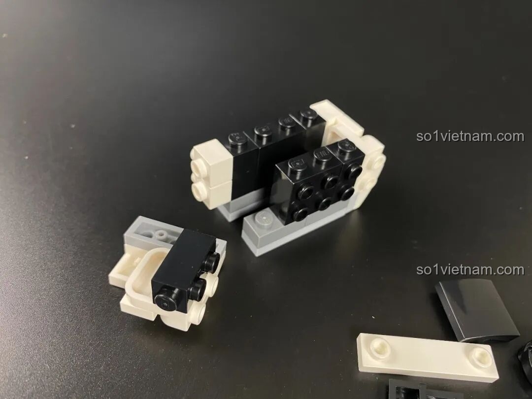 Quá trình lắp ráp phần đầu của mô hình Keeppley Pochacco KUPPY, sử dụng các khối gạch đen và trắng.