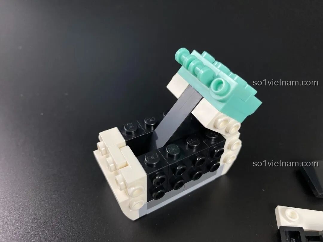 Quá trình lắp ráp phần tai của figure Pochacco, sử dụng các mảnh ghép màu đen và trắng.