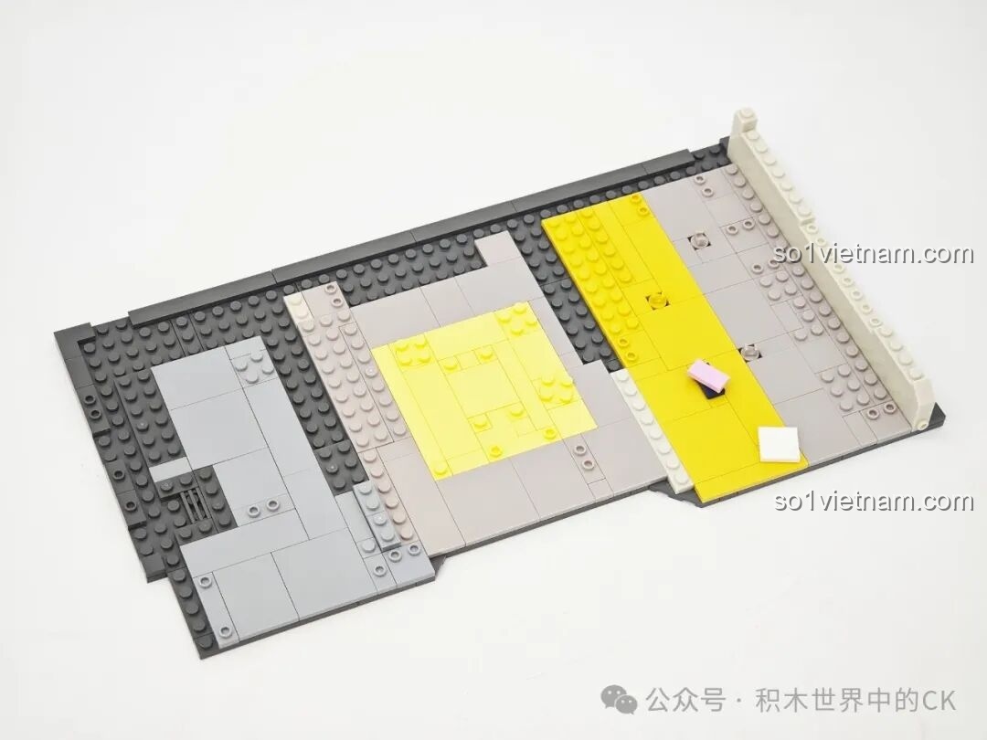 Lắp ráp phần sàn nhà của mô hình Reply 1988, sử dụng các mảnh ghép màu xám, đen và vàng để phân chia khu vực.