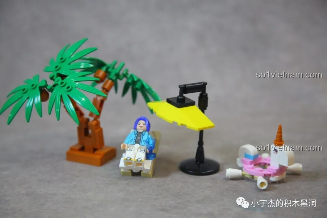 Minifigure cô gái đi biển của bộ Sembo 714510 đang ngồi thư giãn trên ghế xếp dưới ô che nắng.