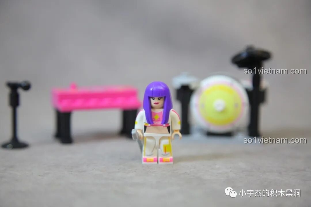 Minifigure nữ rocker tóc tím cá tính của bộ Sembo 714508 đứng cạnh các nhạc cụ, sẵn sàng biểu diễn.