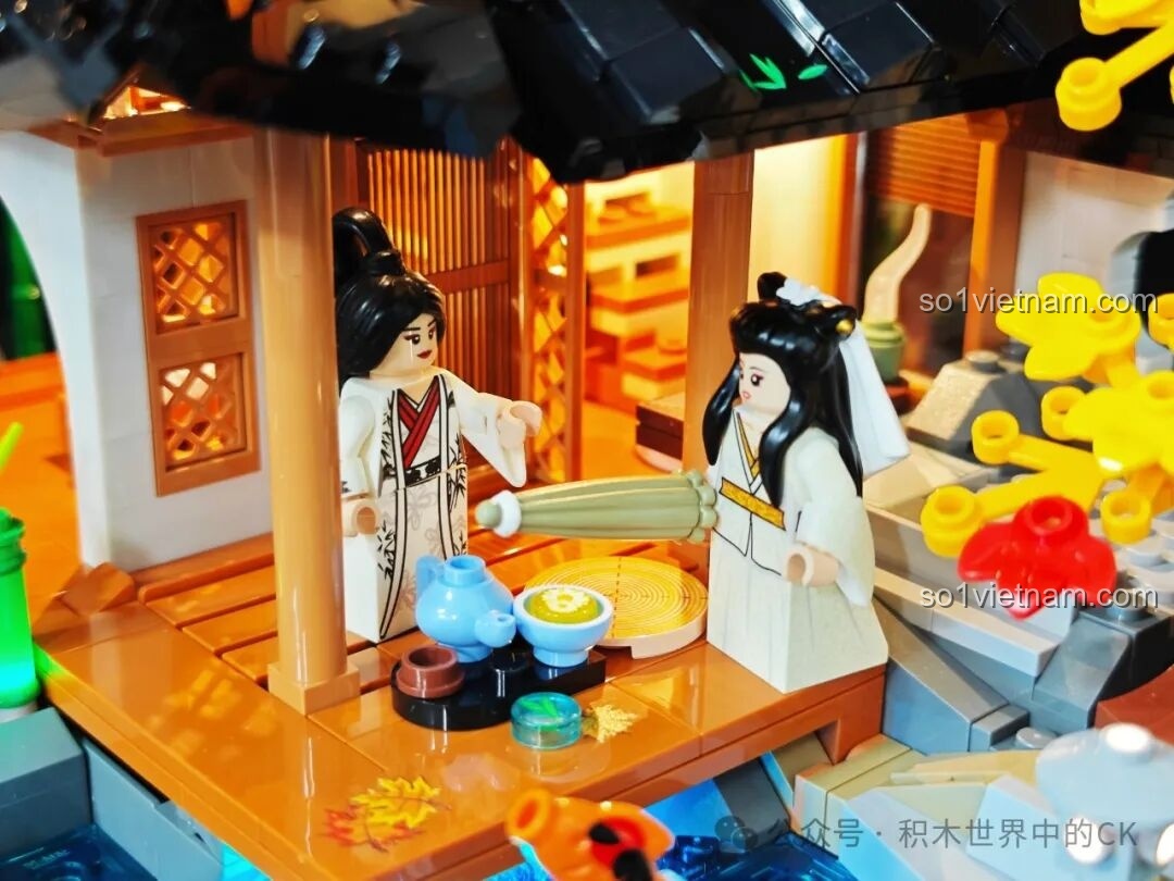 Hai minifigure cổ trang đang thưởng trà trên hiên nhà của mô hình, tạo nên một khung cảnh yên bình và thơ mộng.