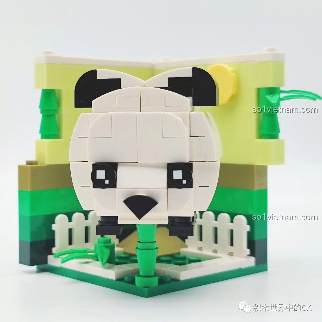 Mô hình lắp ráp Rubik hình gấu trúc đã hoàn thiện, ngồi giữa sa bàn rừng tre xanh mướt và nền vàng chanh.