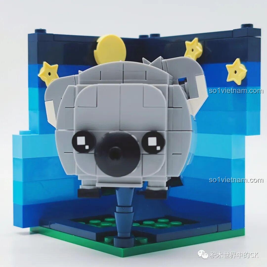 Mô hình lắp ráp Rubik hình koala màu xám đã hoàn thiện, trên sa bàn có nền trời đêm và các ngôi sao vàng.