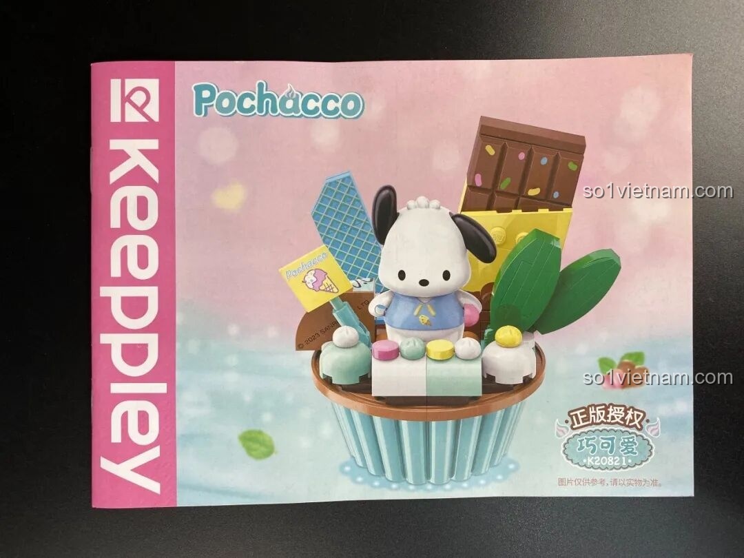 Mở hộp bộ lắp ráp Pochacco cupcake, bên trong có túi chi tiết và sách hướng dẫn lắp ráp nhỏ gọn.