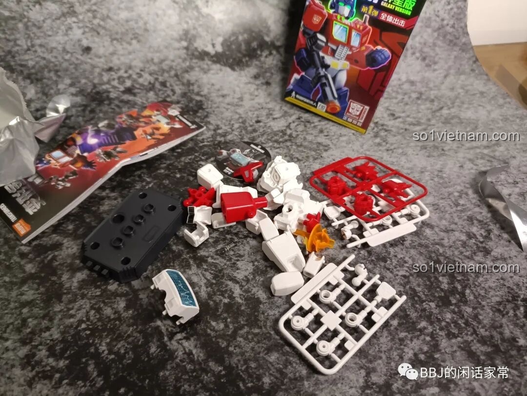 Các chi tiết để lắp ráp figure Ratchet từ bộ BLOKEES 71100 được đặt trên các vỉ nhựa, cùng với sách hướng dẫn và đế trưng bày.