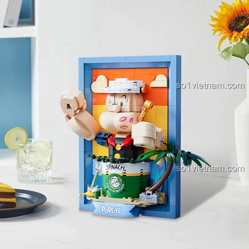 Mô hình Popeye 86403 được trưng bày trên bàn cạnh đồ uống, thể hiện tính nghệ thuật và trang trí của sản phẩm.