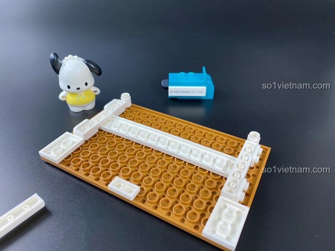 Quá trình lắp ráp phần đế của bộ xếp hình Chú Chó Pochacco Keeppley, bắt đầu với các mảnh ghép màu trắng và nâu.
