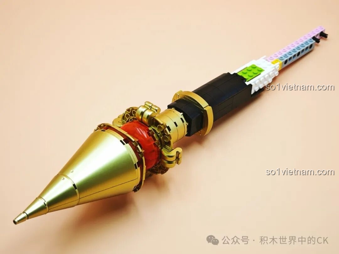 Phần đuôi của JIESTAR 58112 Trượng Hộ Ma Genshin Impact với chóp nhọn màu vàng đồng đang được lắp ráp, tạo sự cân đối.