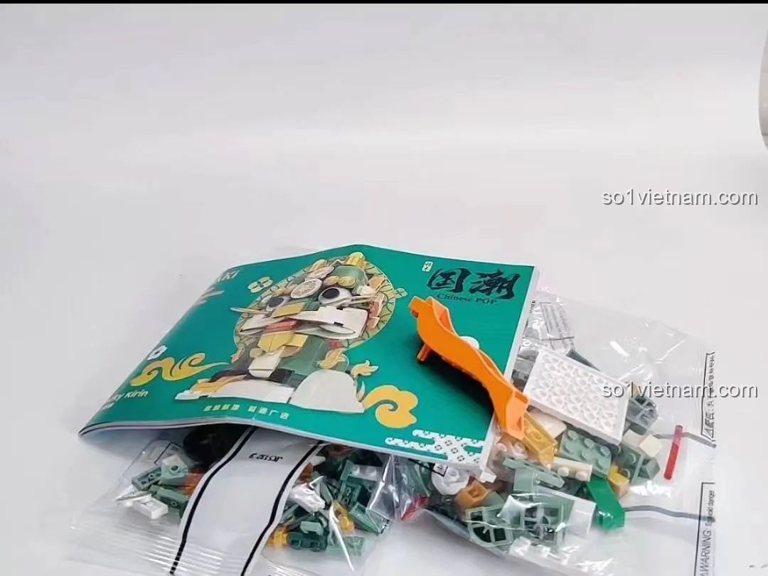 Nội dung bên trong hộp đồ chơi lắp ráp Kỳ Lân Chiêu Tài JK5132 JAKI gồm mảnh ghép, sách hướng dẫn và tách gạch.