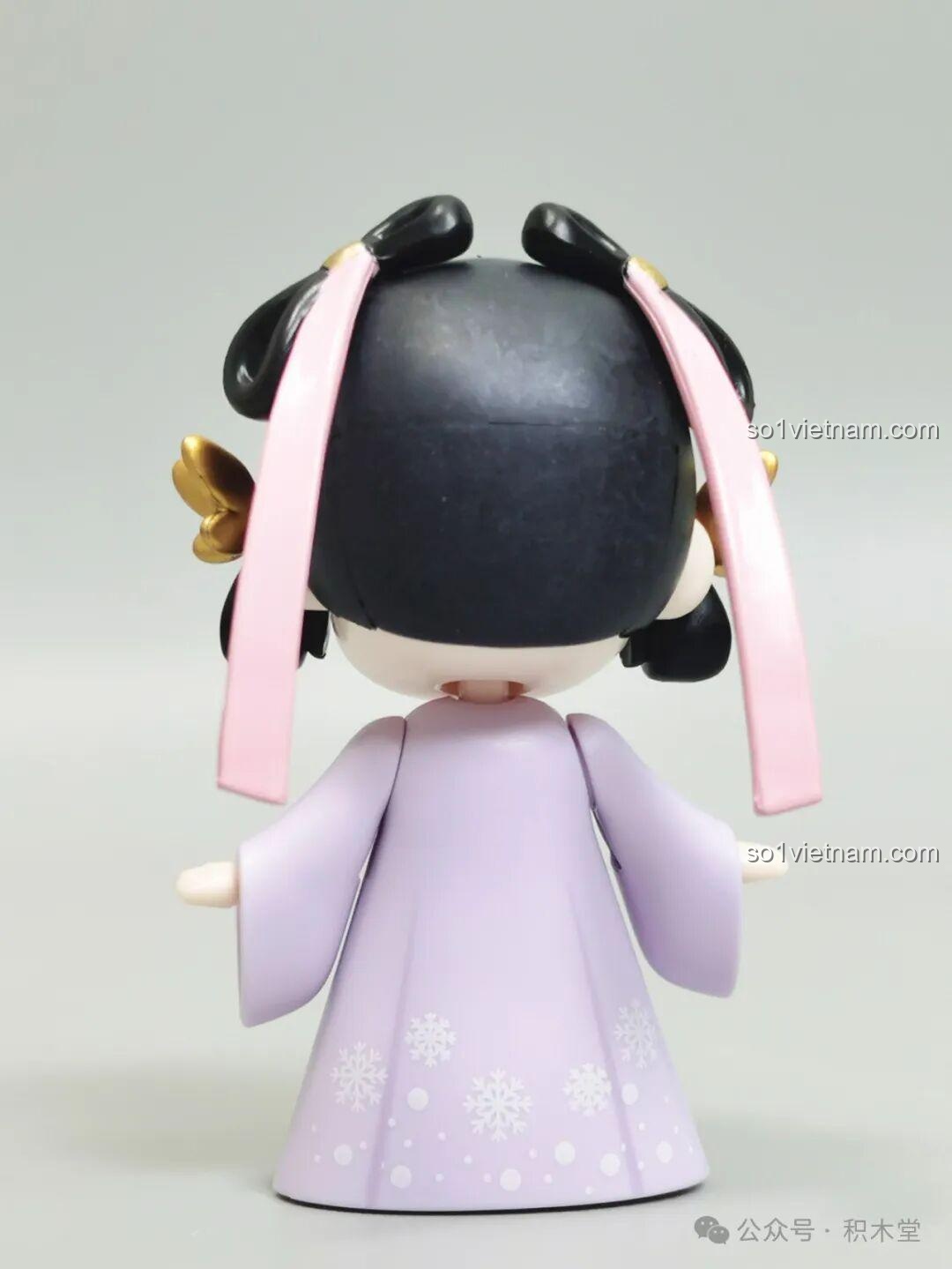 Mặt sau của minifigure Nanci mùa Đông, cho thấy chi tiết kiểu tóc và dải ruy băng hồng trang trí.