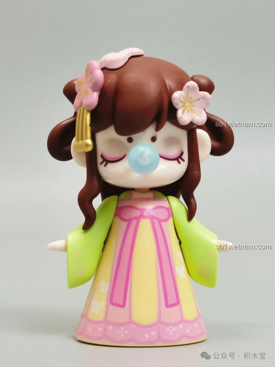 Cận cảnh minifigure Nanci mùa Xuân với trang phục cổ trang màu hồng vàng, tóc cài hoa và bong bóng thổi từ mũi đặc trưng.