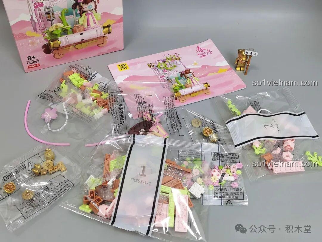 Bên trong hộp đồ chơi TOP TOY Nanci mùa Xuân TC2053, bao gồm các túi mảnh ghép, sách hướng dẫn và các chi tiết đặc biệt.