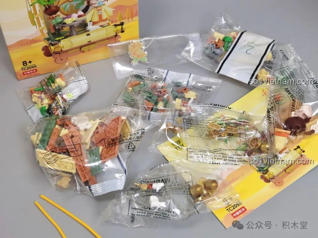 Bên trong hộp đồ chơi TOP TOY Nanci mùa Thu TC2055, với các túi mảnh ghép mang tông màu vàng, cam và xanh rêu ấm áp.