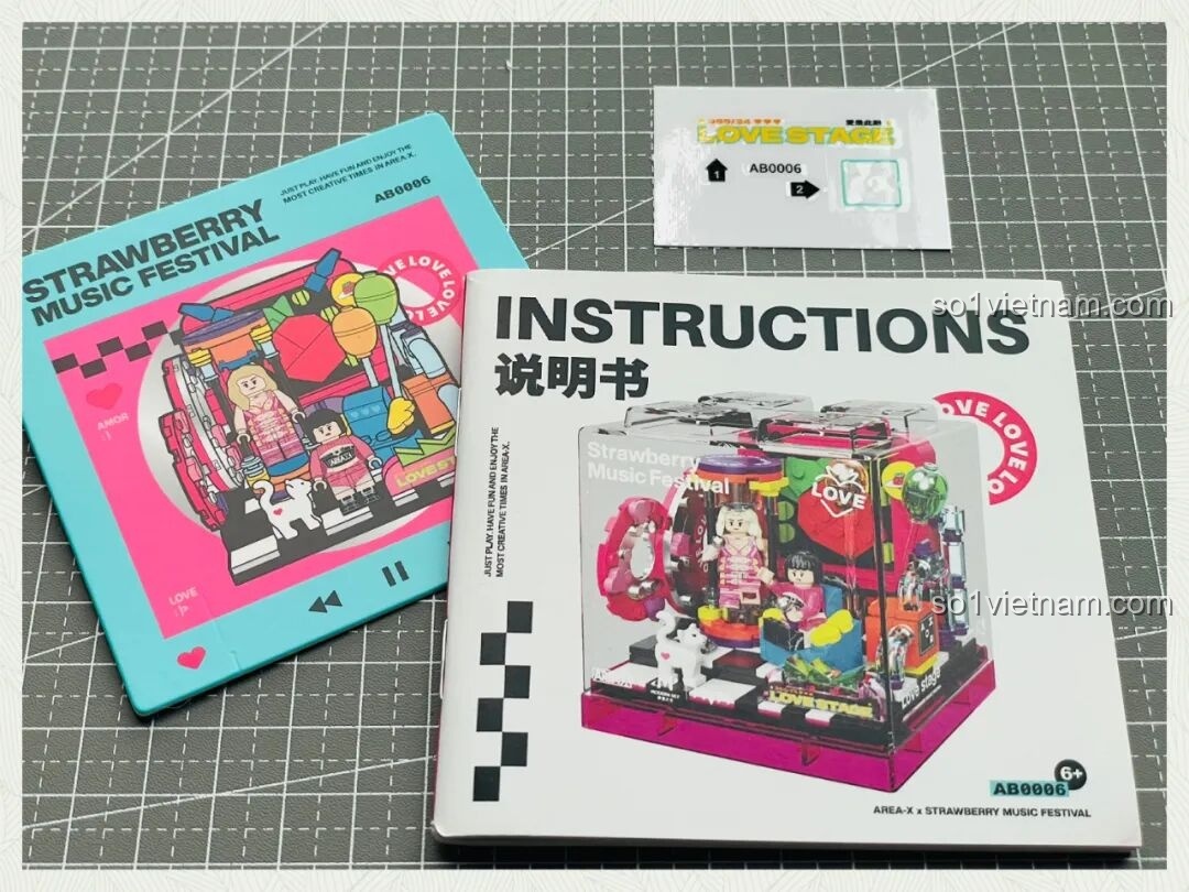 Sách hướng dẫn lắp ráp và tờ sticker đi kèm bộ đồ chơi Ái Vũ Đài AREA-X AB0006, với hình ảnh mô hình và logo Strawberry Music Festival.