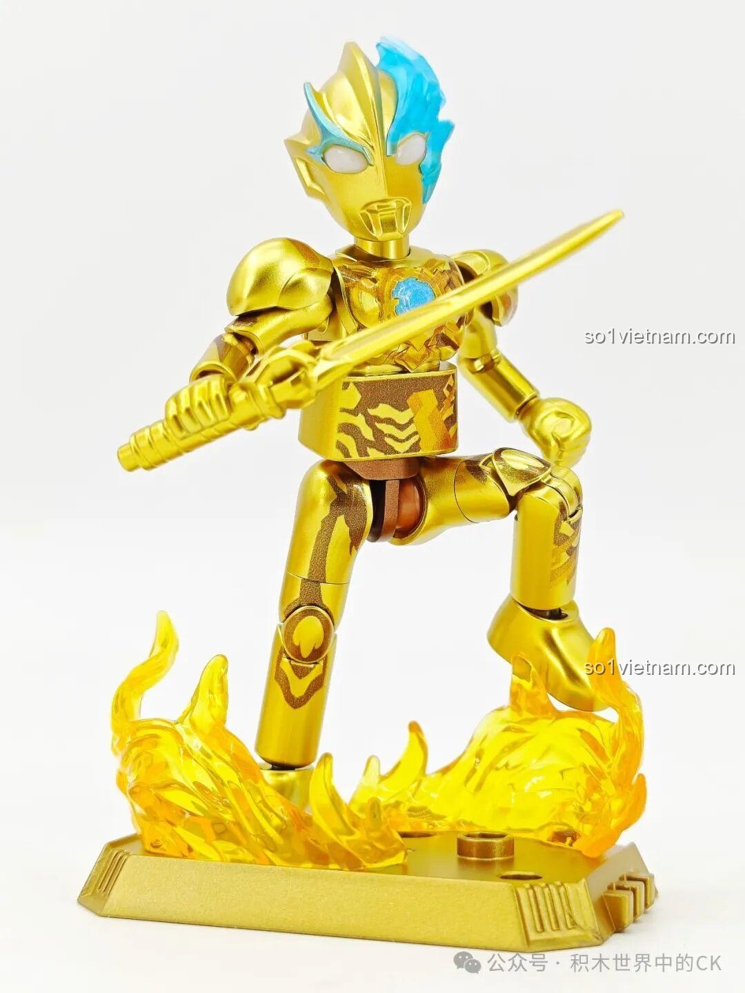 Ultraman Blazar phiên bản vàng tạo dáng chiến đấu trên đế trưng bày với hiệu ứng lửa, một hình ảnh ấn tượng cho bộ sưu tập.