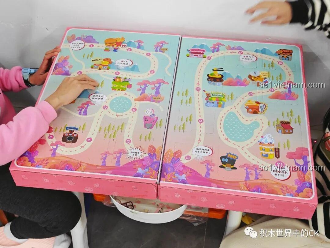 Một bé gái đang chuẩn bị chọc vào ô cửa đầu tiên trên hộp quà QMAN 35018, bắt đầu hành trình khám phá 21 món ăn.