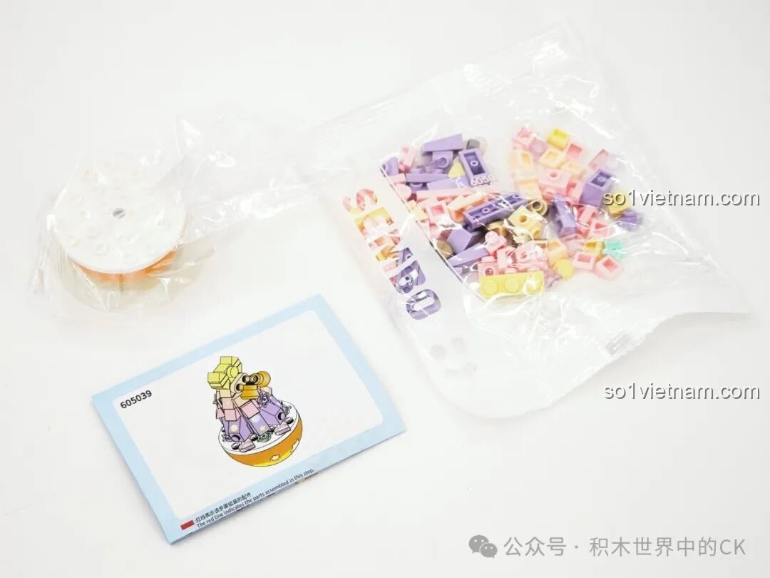 Bên trong hộp 605039: các mảnh ghép màu pastel và sách hướng dẫn, chuẩn bị lắp ráp Cây Thông Chuông.