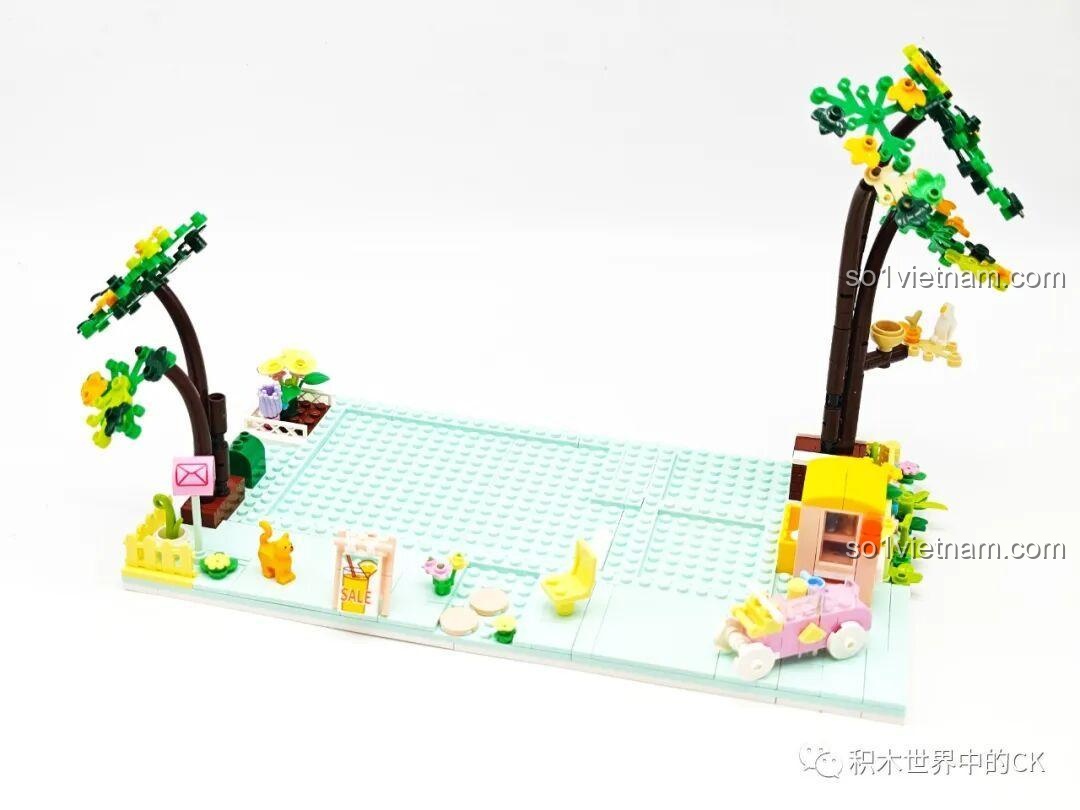 Giai đoạn đầu của quá trình lắp ráp bộ xếp hình ZHEGAO 612003 Cửa hàng trà chanh, với phần đế và cây cối cơ bản.